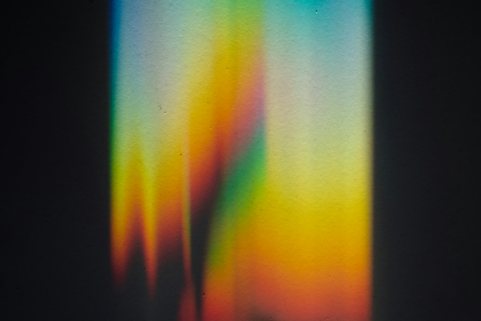 a prism splitting a single beam of light into a rainbow spectrum against a dark background
